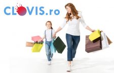 happy young mother and cute little daughter holding shopping bags and walking together isolated on white